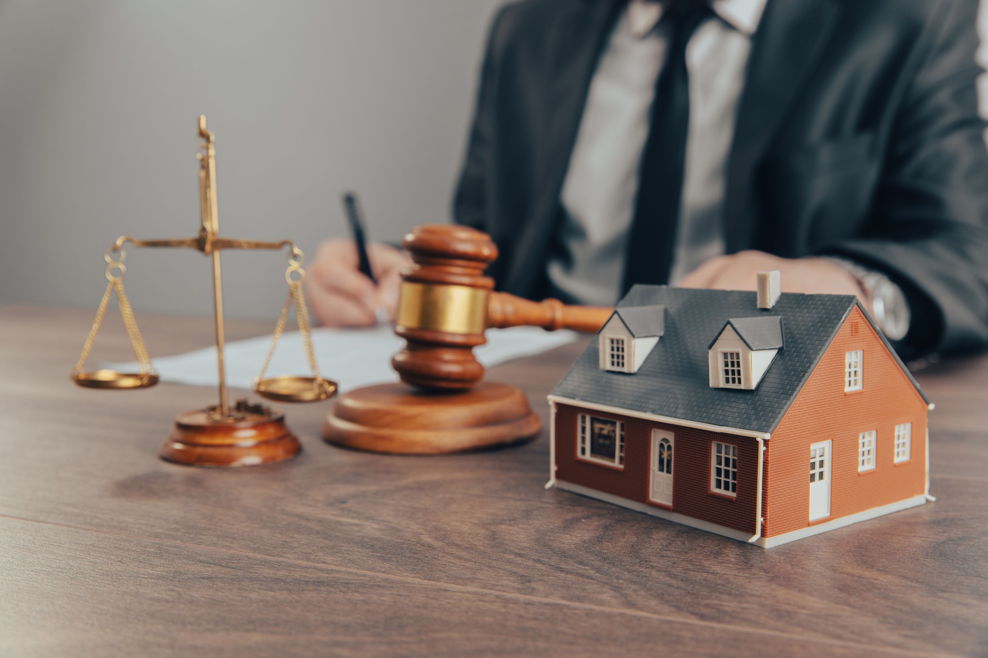 A mão de um juiz com um martelo e um modelo de uma casa mediando disputas de propriedade no tribunal