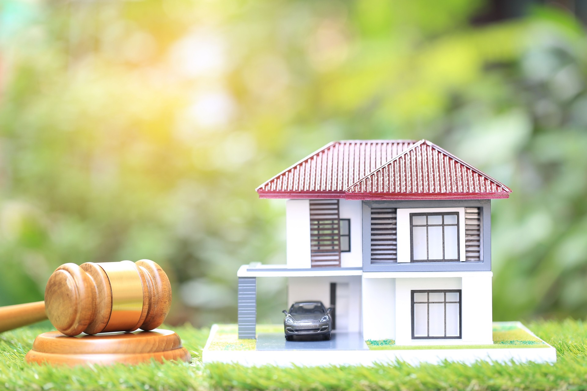 Leilão de propriedade, martelo de madeira e casa modelo em fundo verde natural, advogado da casa real estate e conceito de propriedade de propriedade